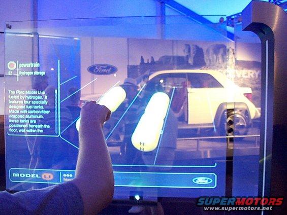 Side view of white Ford Model U concept car on interactive display with powertrain information