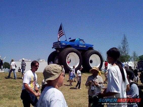 Blue monster truck with oversized tires and an American flag on the roof