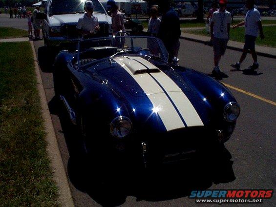 Blue convertible sports car with white racing stripes parked on a street