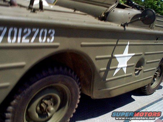 Olive drab amphibious vehicle with white star insignia and serial number 7012703 on the side