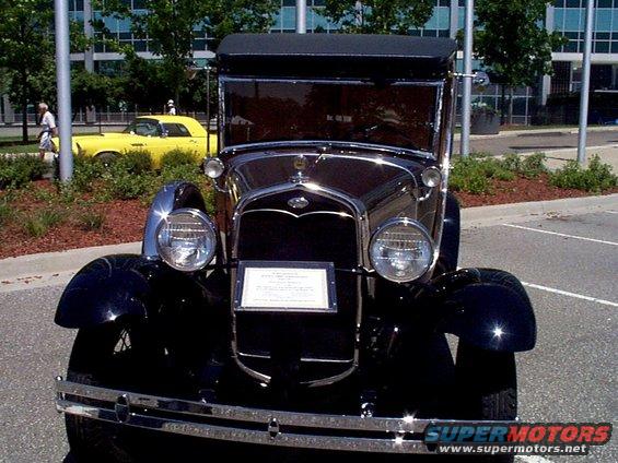 Front view of a black vintage Ford with a plaque on the grille