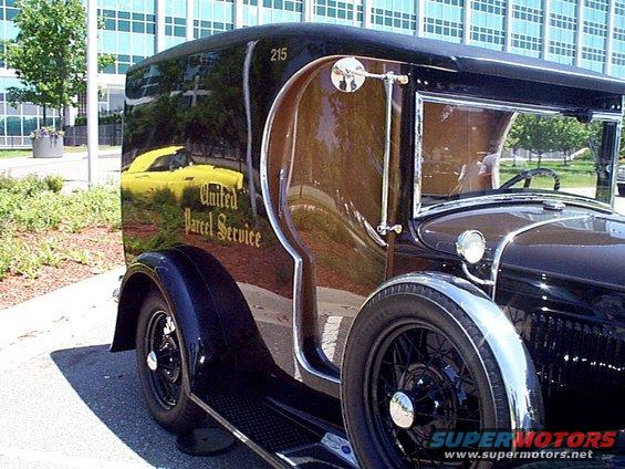 Black vintage United Parcel Service delivery truck with yellow car reflected in its side