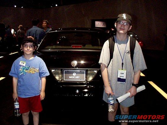 Black Mercury Grand Marquis rear, license plate area visible, two boys standing in front