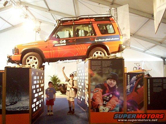 Orange Land Rover Discovery with G4 Challenge graphics, displayed elevated above exhibit panels