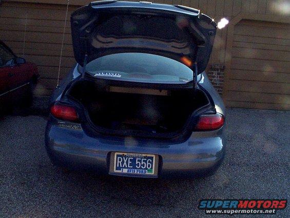 Rear view of a dark blue 1999 Ford Taurus with open trunk and license plate RXE 556