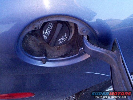 Blue car fuel door with warning text on cap