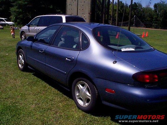 Blue 1999 Ford Taurus sedan parked on grass, rear 3/4 view