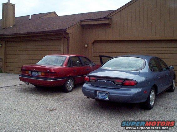 blue sedan and red sedan parked in front of a house with garages