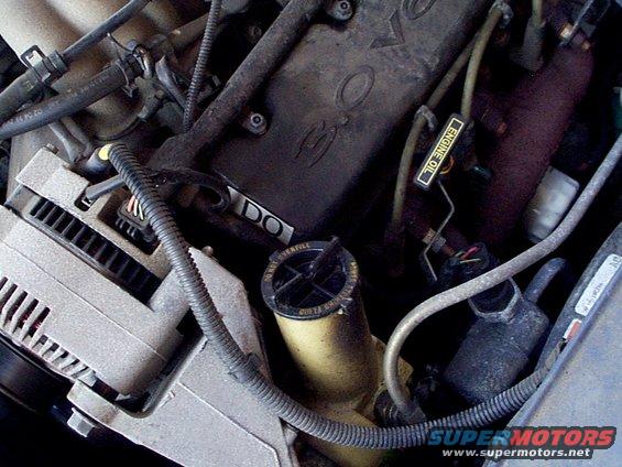 Engine bay detail showing alternator, fluid reservoir, and engine cover with 'DO' visible