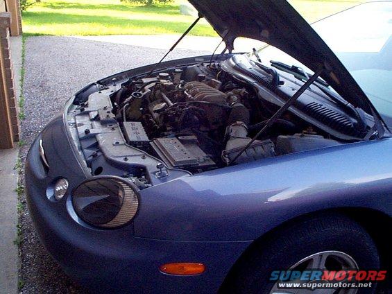 Blue 1999 Ford Taurus with hood open, showing engine and front quarter panel