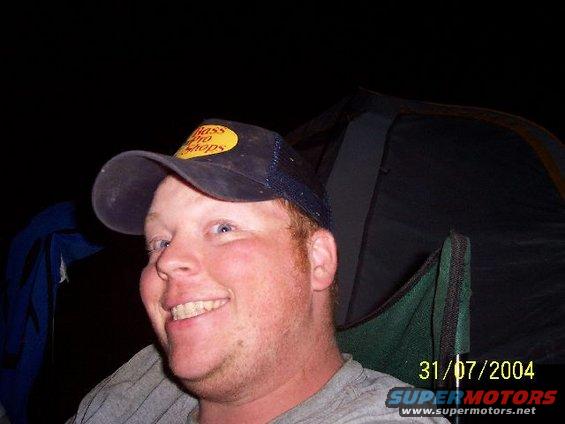 Man in Bass Pro Shops hat, outdoor scene with tent