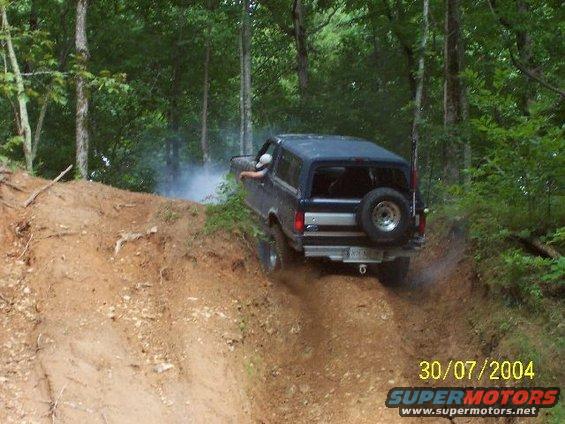 Dark blue 1995 Ford Bronco climbing a dirt hill with smoke coming from the exhaust