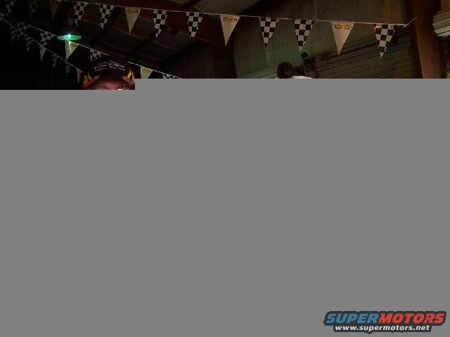 Checkerboard and triangular racing flags hang from a ceiling, with a person's head visible below
