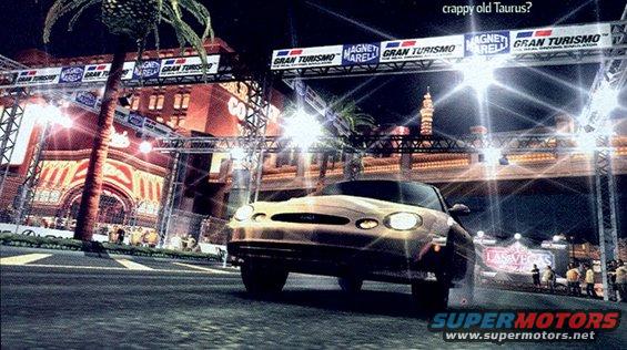 Gold 1999 Ford Taurus driving on a race track at night, with bright lights and palm trees