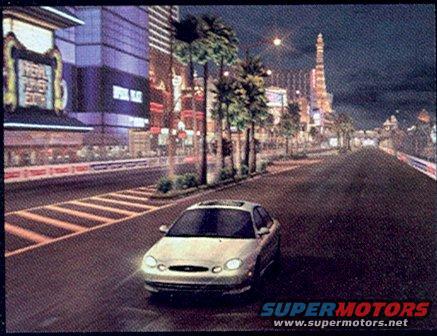 Silver 1999 Ford Taurus driving on a neon-lit street at night