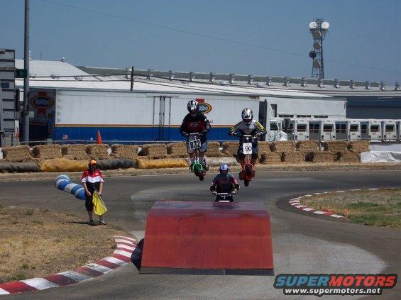 Scooters jump a ramp, one with number 90, another with 832