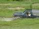 1995 Ford Bronco - A Ford Bronco navigates a muddy, grassy terrain, with a driver visible inside the vehicle.
