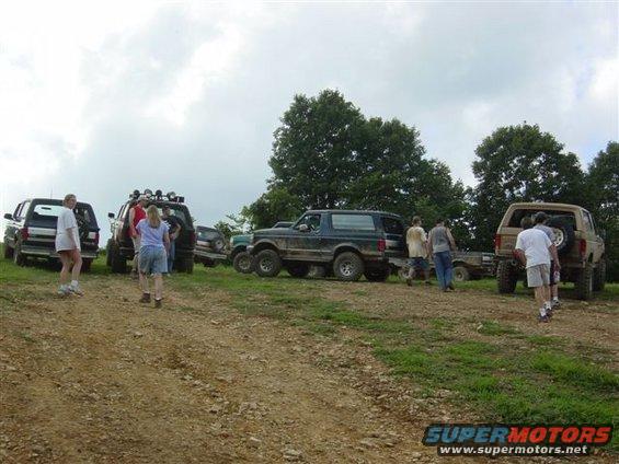 Dark blue Ford Bronco parked on a dirt hill with people around it