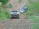 1995 Ford Bronco - Two SUVs navigate a steep, muddy incline during an off-road excursion.