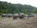 1995 Ford Bronco - Several off-road vehicles are gathered in a muddy area, with one red Bronco appearing to be stuck.
