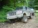 1995 Ford Bronco - Two SUVs, including a 1995 Ford Bronco, navigate a rough, wooded trail.