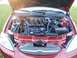 2000 Ford Taurus - The engine bay of a red Ford Taurus is visible with the hood open, highlighting the Duratec V6 engine.