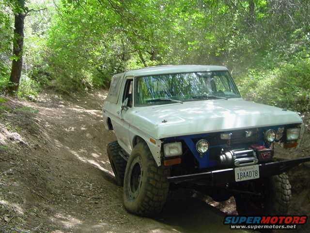 White off-road SUV with winch and license plate 1BAAD78 on a dirt trail