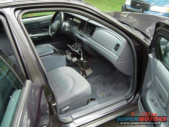 Dark purple sedan interior, gray cloth seats, dashboard with radio and vents. Another blue car is visible outside