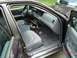 1999 Ford Crown Victoria - The interior of a dark purple sedan shows gray cloth seats and a dashboard with a radio and air vents. A blue vehicle is visible through th…