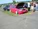 1990 Jeep YJ - A red hatchback with its hood open is parked on grass next to other vehicles at an outdoor event.