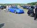 1990 Jeep YJ - A bright blue Audi sedan is the focus of this outdoor car show scene, with other vehicles and attendees around.