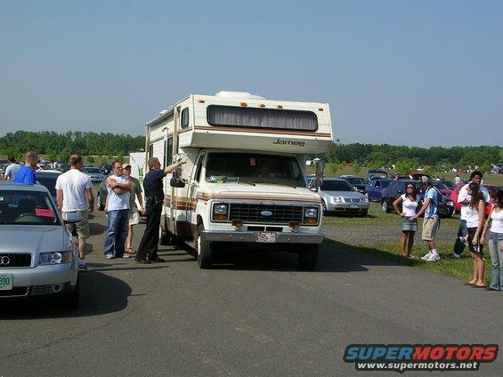 Motorhome with 'Jamee' on the side, facing forward, with people around