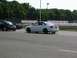 1990 Jeep YJ - A white sedan with black wheels drives on a race track alongside other vehicles.