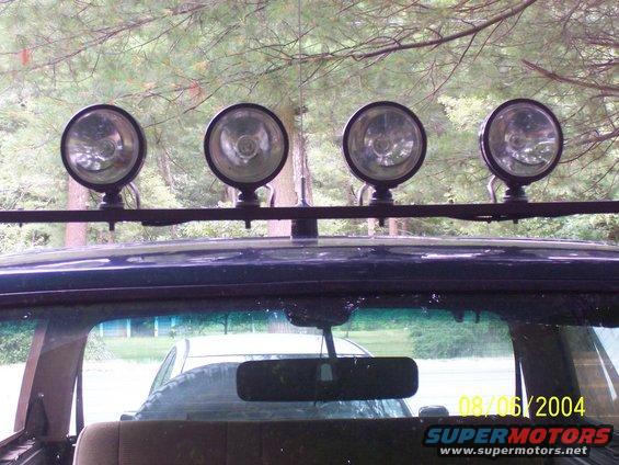 Dark blue SUV roof with a light bar holding four spotlights, seen from inside