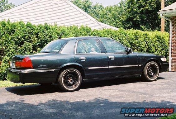 Dark sedan parked on driveway, side view. Looks like a 1998 Mercury Grand Marquis