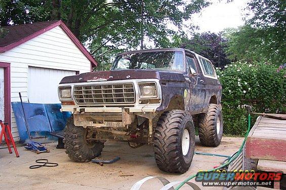 1978 Ford Bronco with large tires, lifted suspension, and custom bumper, parked in a driveway