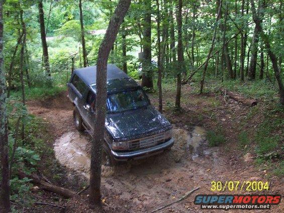 1995 Ford Bronco on a muddy forest trail