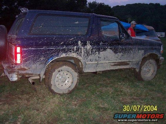 1995 Ford Bronco covered in mud, parked on grass