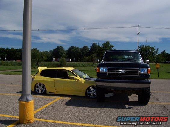 Black 1989 Ford F-Series truck front view, parked next to a yellow Honda Civic