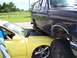 1989 Ford Bronco - A Ford Bronco is parked on top of a yellow car, with the Bronco's front wheel visible.