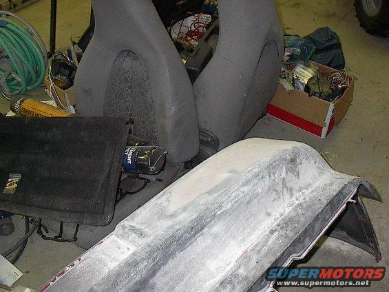 Car seats and parts in a workshop setting. A bumper is in the foreground