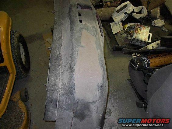 car bumper being repaired with body filler, yellow lawn tractor wheel visible
