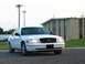 2000 Ford Crown Victoria - A white 2000 Ford Crown Victoria is parked in front of a building.