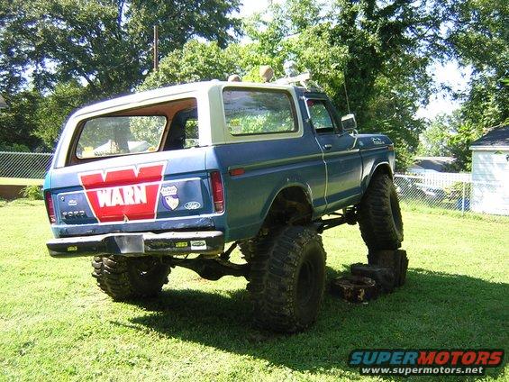 Blue Ford Bronco with lifted suspension and large tires, WARN logo on tailgate