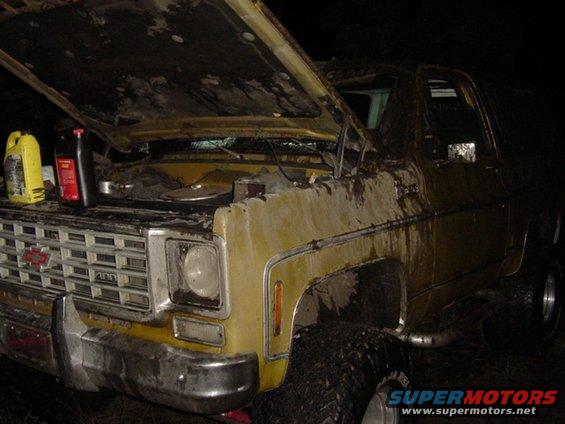 Old yellow Chevrolet pickup truck, hood open, with bottles of fluid on engine