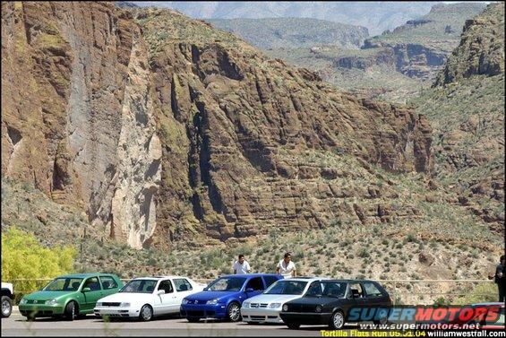 Several Volkswagen Golfs parked in a desert canyon with rocky cliffs