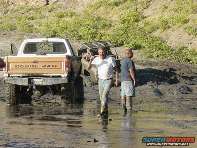 Dodge Ram pickup truck stuck in mud with two guys standing nearby