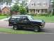 1988 Ford Bronco - A black Ford Bronco is parked on the side of a residential street in front of a suburban house.