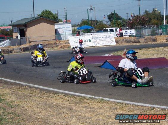 Go-karts racing on a track with drivers wearing helmets. Numbers visible on karts include 6, 827, and 33