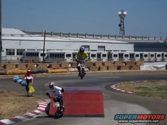 Electric scooter rider jumps over obstacle, another follows